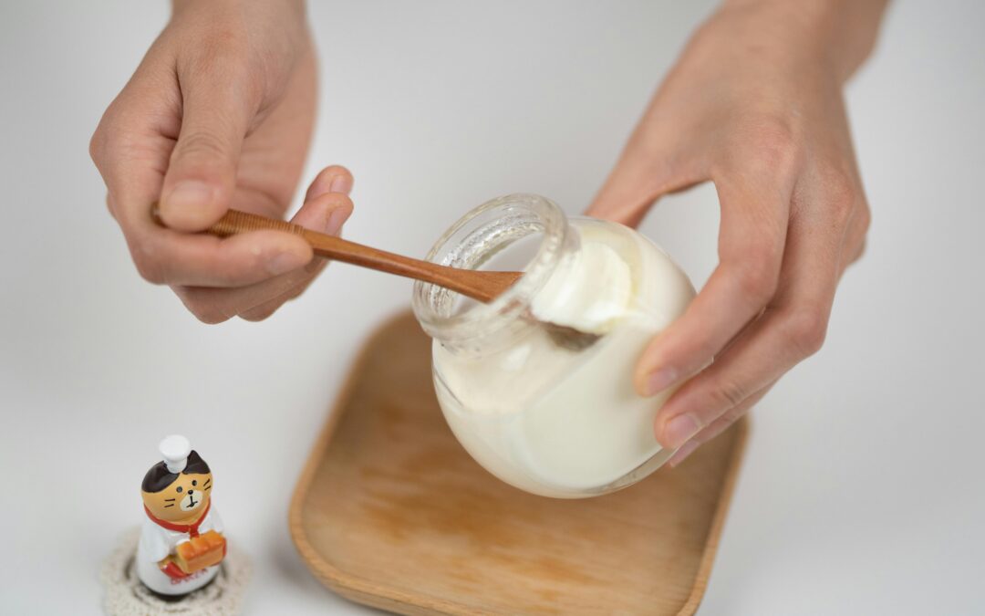 Crop man taking natural yogurt with spoon from jar